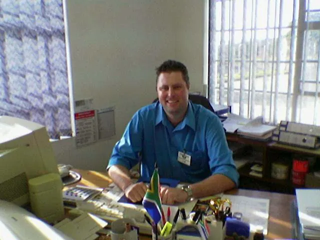 Ashley Deutschmann at his desk on 20 May 2004 beside a CRT monitor and a small South African flag